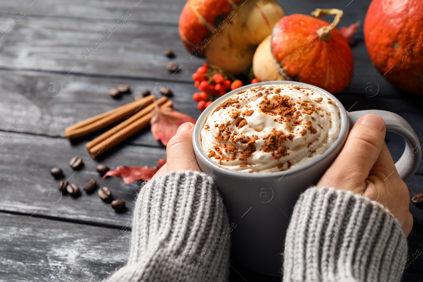 Photo of Woman with cup of tasty pumpkin spice latte at grey wooden table, closeup
