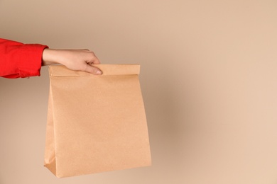 Photo of Woman holding paper bag on color background. Mockup for design