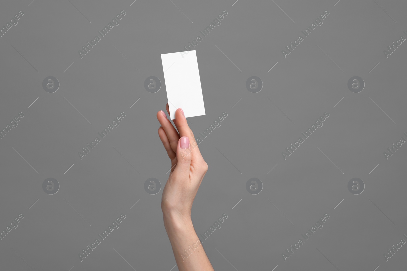 Photo of Woman holding blank business card on grey background, closeup. Space for text