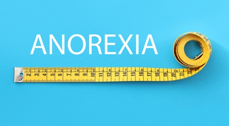 Image of Anorexia concept. Yellow measuring tape on light blue background, top view