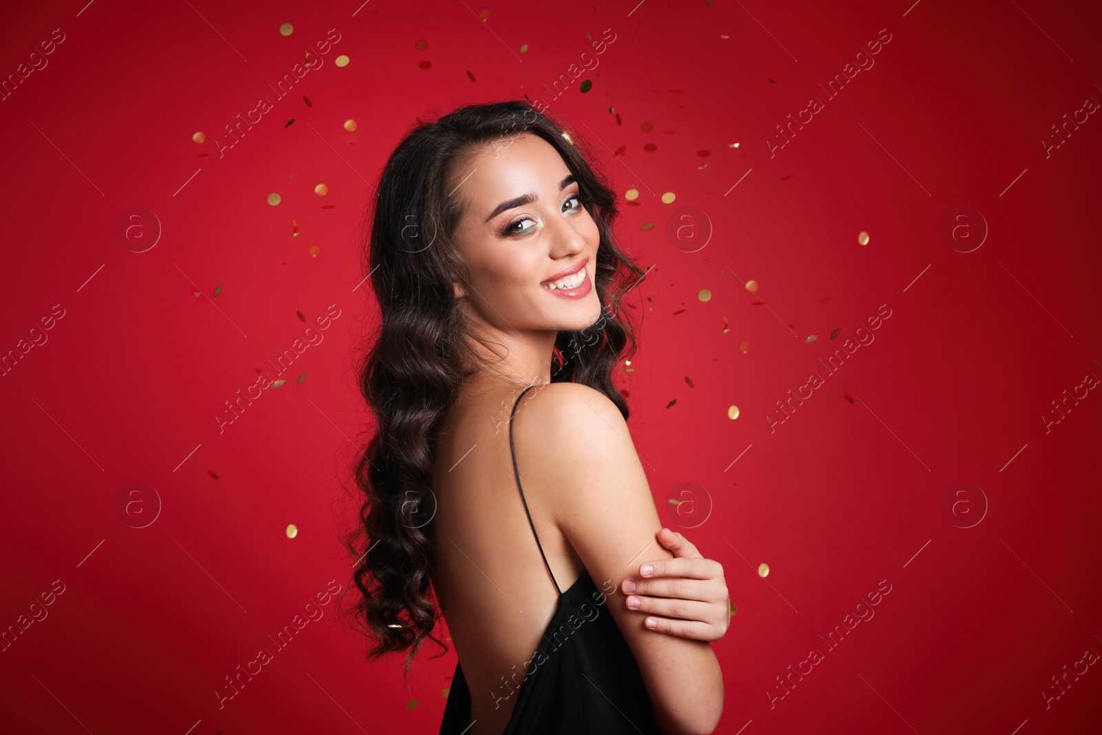 Photo of Beautiful young woman wearing elegant dress on red background. Christmas party