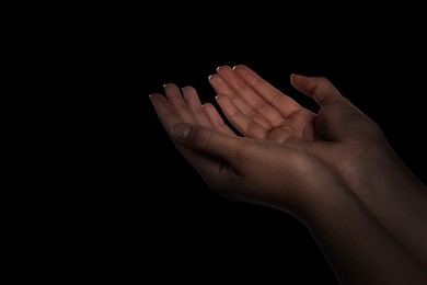Image of Christian woman praying in darkness, closeup. Space for text