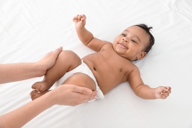 Mother and her cute child on white bed, above view. Baby massage and exercises