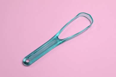 Photo of One turquoise tongue cleaner on pink background