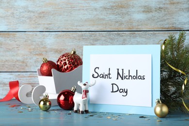 Card with text Saint Nicholas Day and festive decor on light blue wooden table