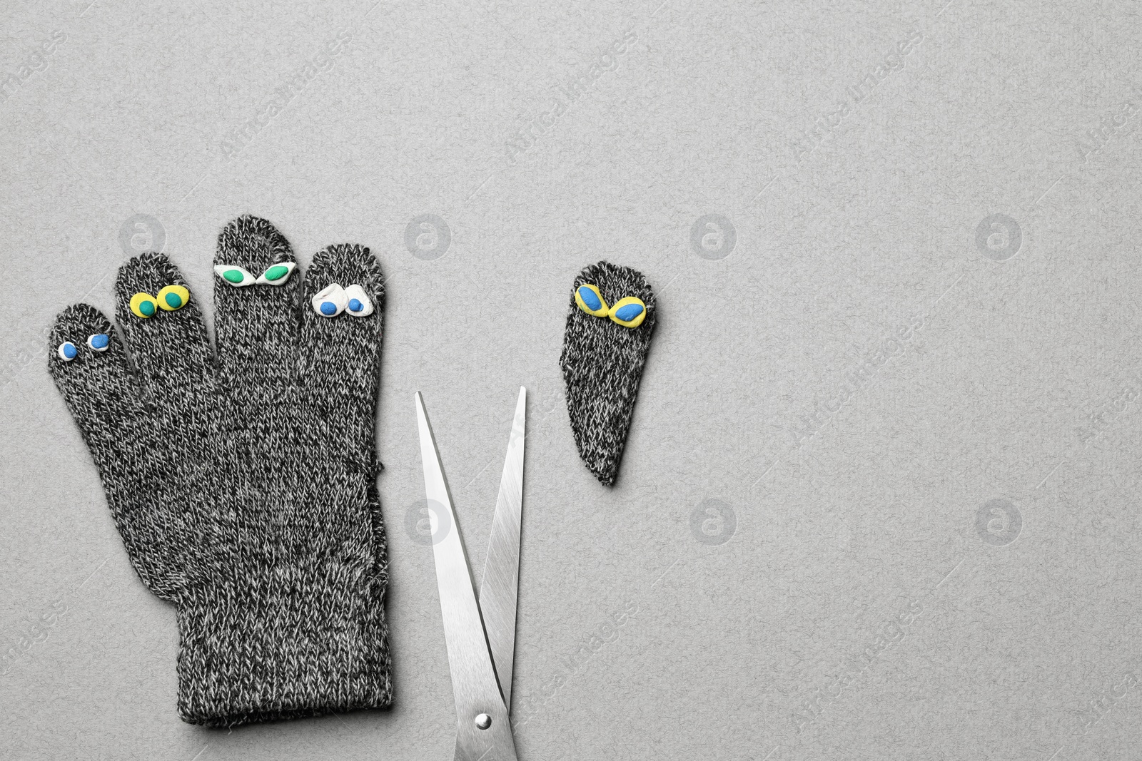 Photo of Divorce concept. Knitted glove and scissors on light grey background, flat lay with space for text