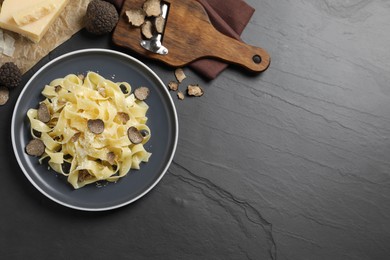 Tasty tagliatelle with truffle on black table, flat lay. Space for text