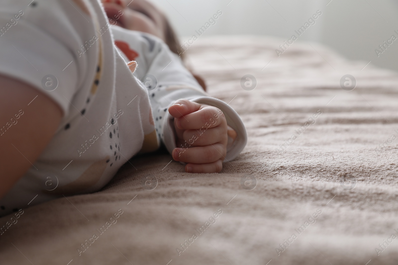 Photo of Little baby lying on brown blanket indoors, closeup. Space for text
