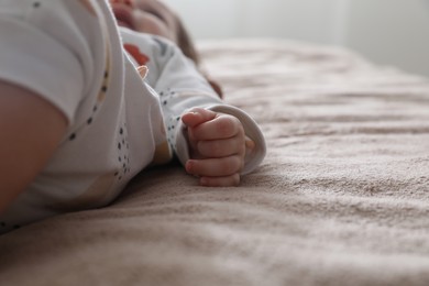 Little baby lying on brown blanket indoors, closeup. Space for text