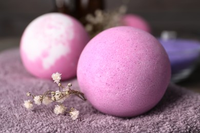 Beautiful aromatic bath bomb and gypsophila flowers on soft towel, closeup