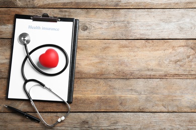 Flat lay composition with health insurance form and stethoscope on wooden background, space for text