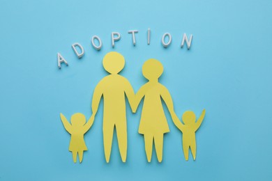 Photo of Family figure and word Adoption on light blue background, flat lay