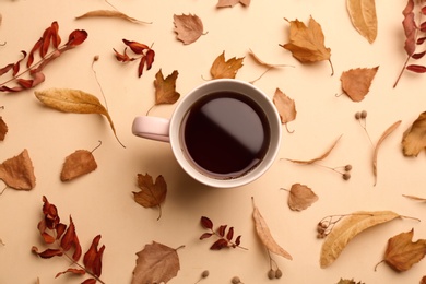 Photo of Flat lay composition with cup of hot drink and autumn leaves on beige background. Cozy atmosphere
