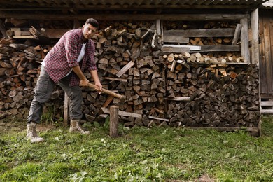 Photo of Man chopping wood near log pile outdoors