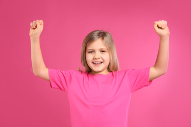 Photo of Happy little girl wearing casual outfit on pink background