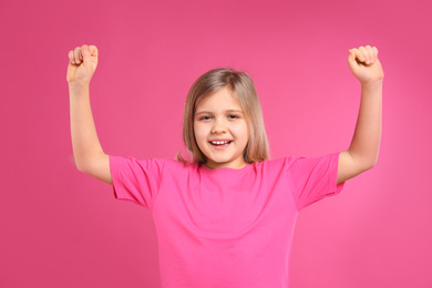 Happy little girl wearing casual outfit on pink background