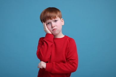 Photo of Portrait of sad little boy on light blue background