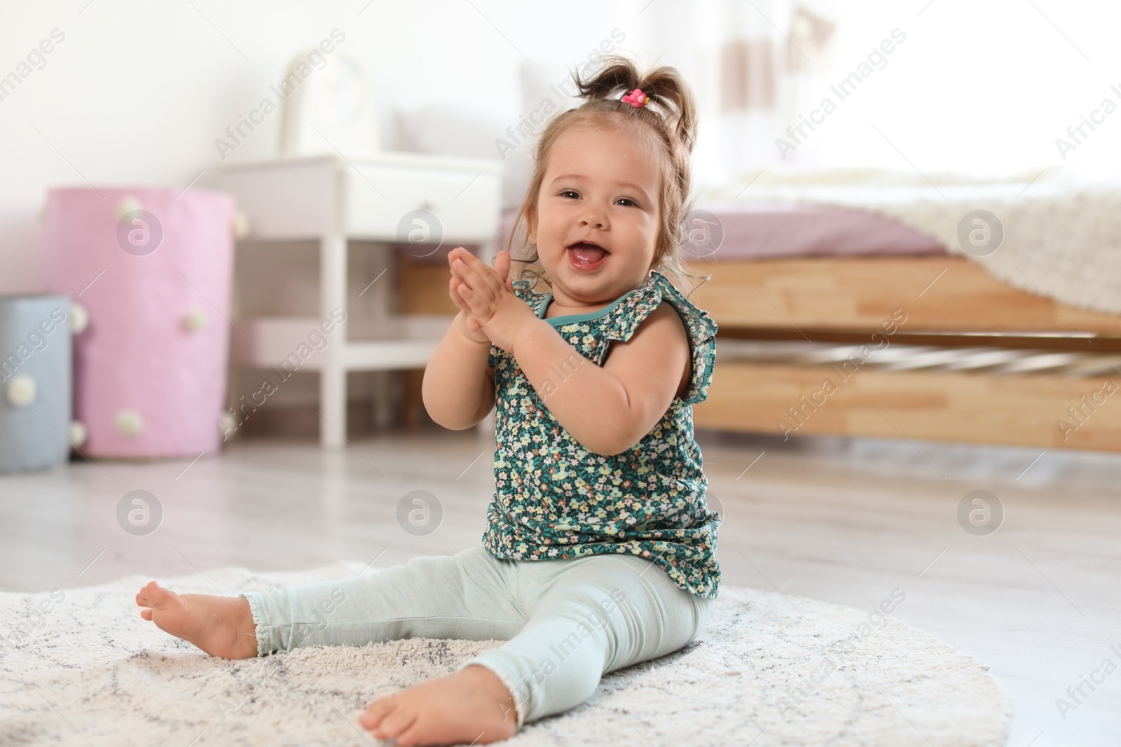 Photo of Adorable little baby girl sitting on floor in room