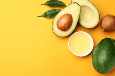 Photo of Cooking oil in bowl and fresh avocados on yellow background, flat lay. Space for text