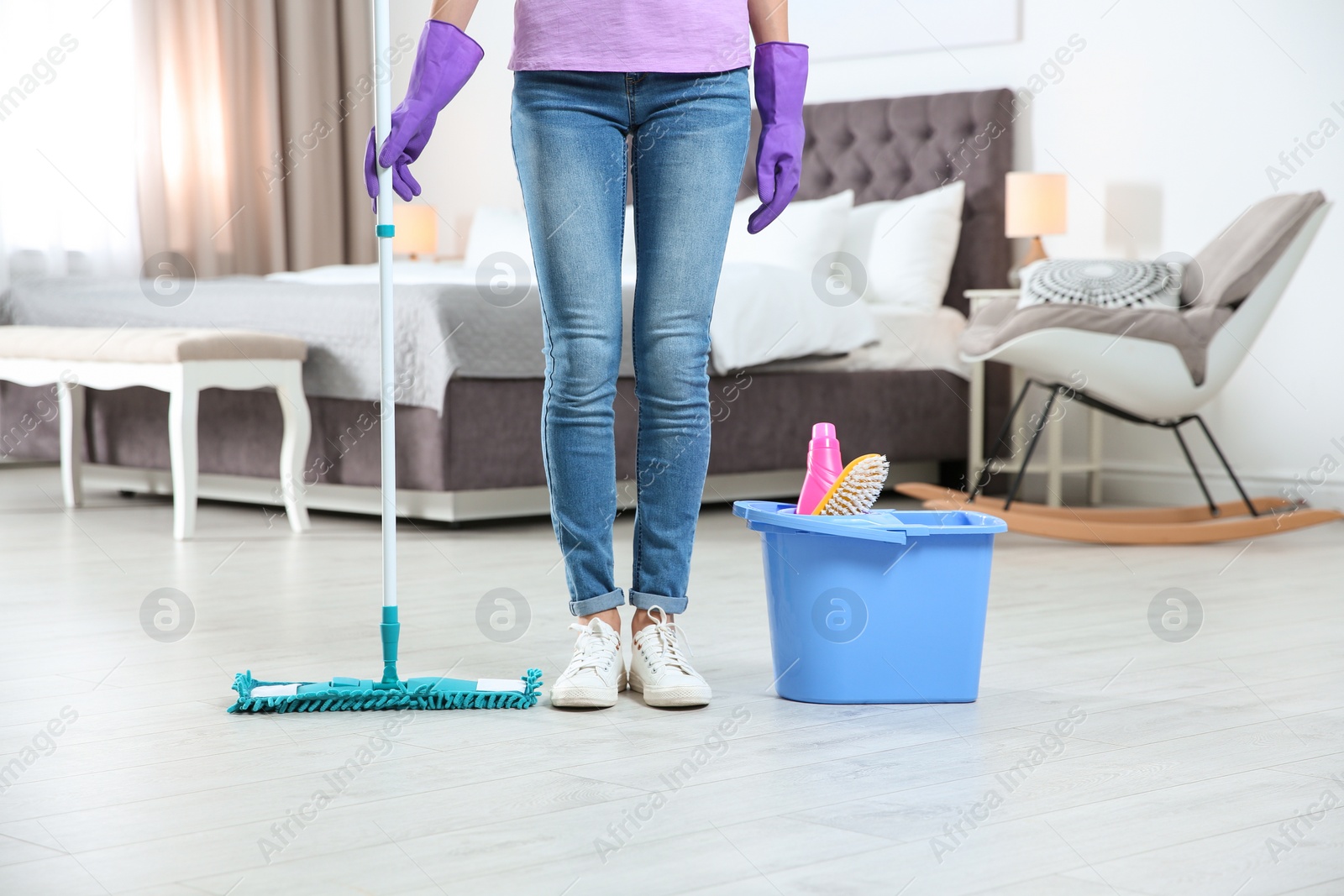 Photo of Young woman with mop and detergents in bedroom, closeup. Cleaning service