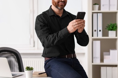 Photo of Smiling man using smartphone in office, closeup