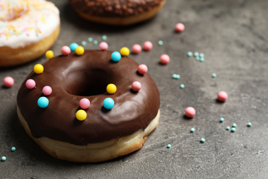 Photo of Yummy donuts with colorful sprinkles on dark background, space for text