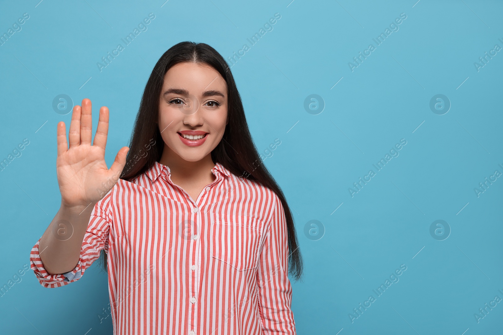 Photo of Happy woman giving high five on light blue background, space for text