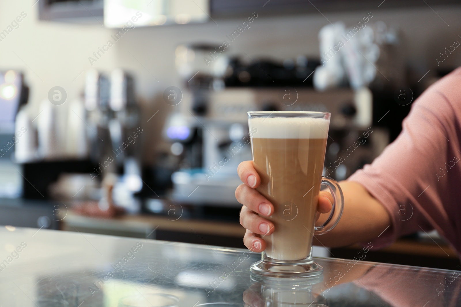 Photo of Barista putting glass with delicious coffee on countertop in cafe, space for text