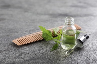 Photo of Stinging nettle, extract and comb on grey background. Natural hair care