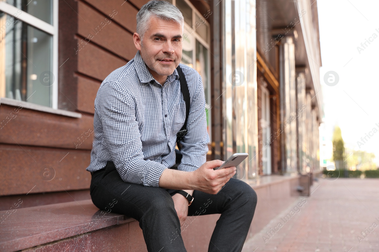 Photo of Portrait of handsome businessman with mobile phone in city, space for text