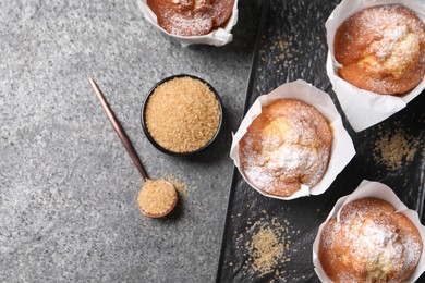 Photo of Delicious muffins and sugar on grey table, flat lay