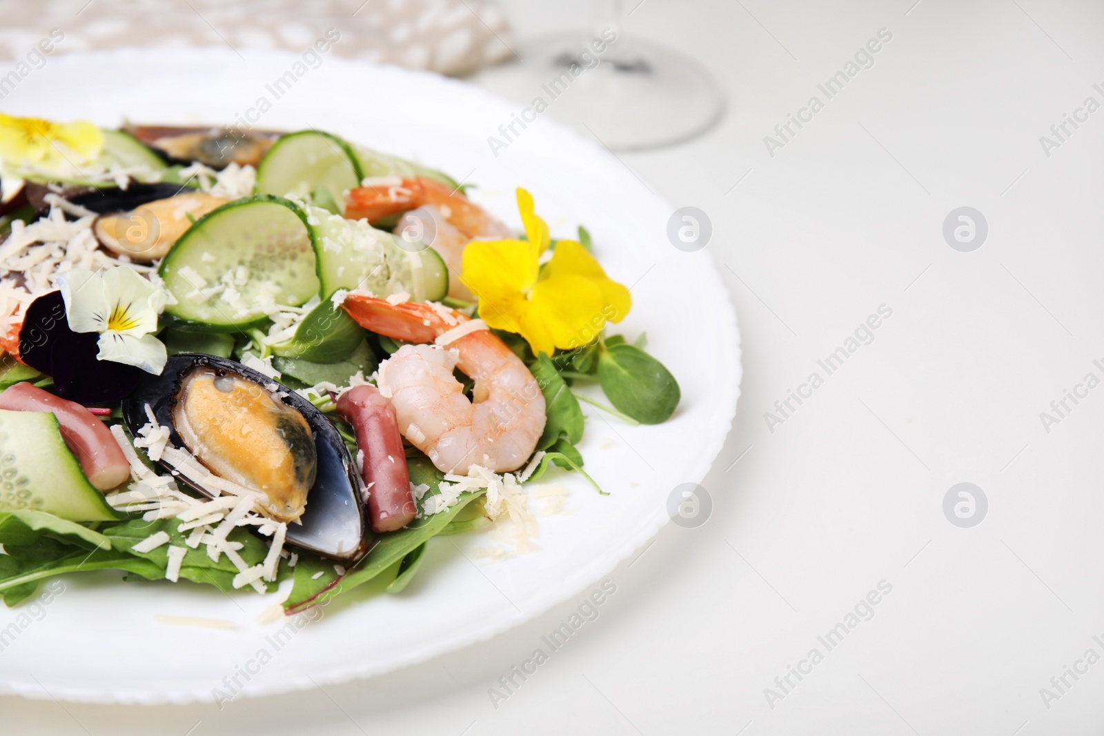 Photo of Plate of delicious salad with seafood on white table, space for text