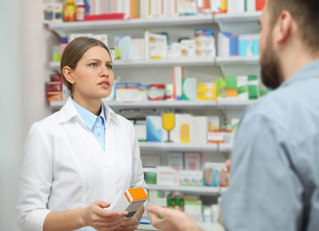 Image of Professional pharmacist working with customer in modern drugstore