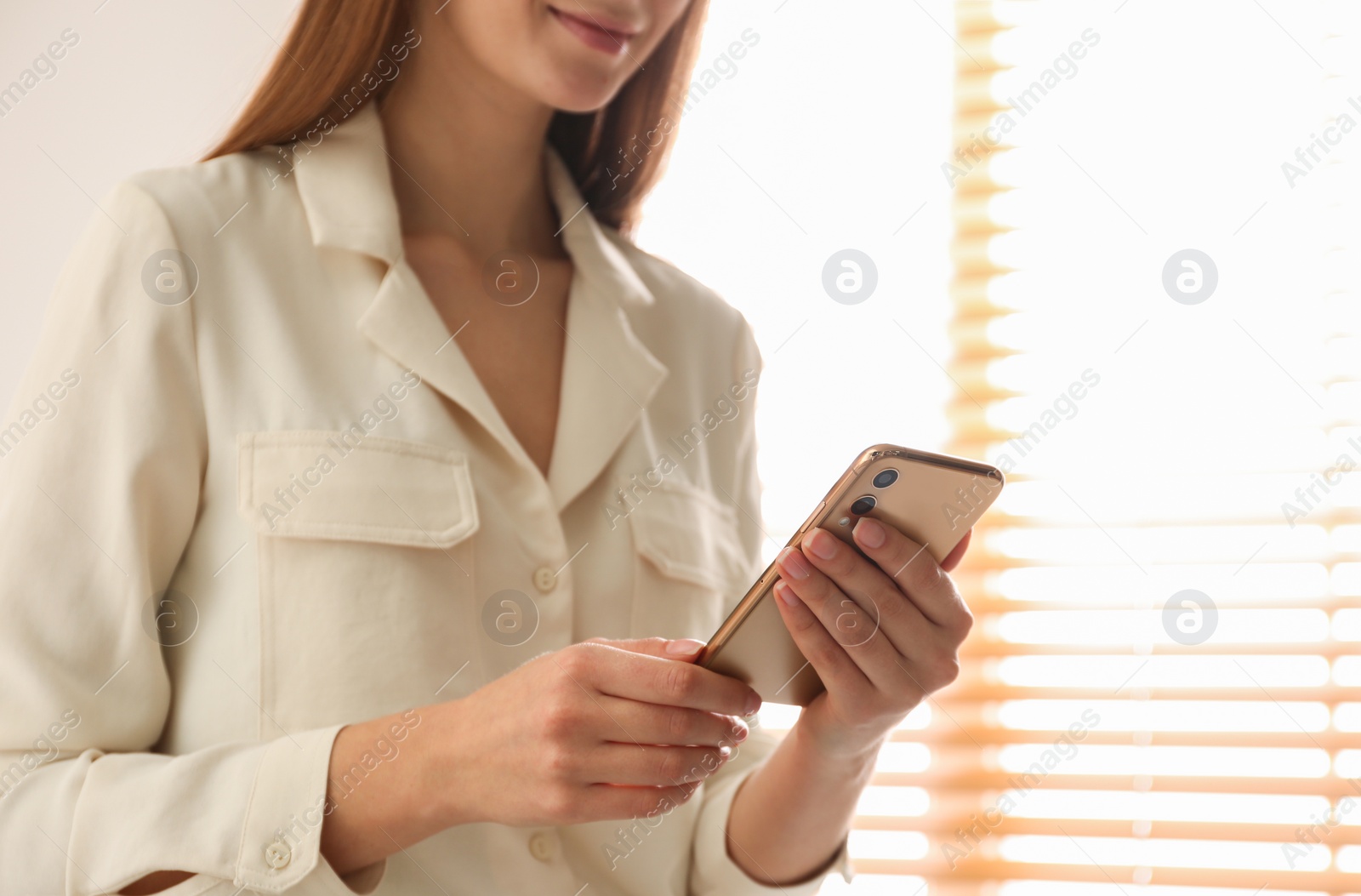 Photo of Young woman using modern smartphone indoors, closeup