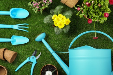 Flat lay composition with gardening equipment and flowers on green grass