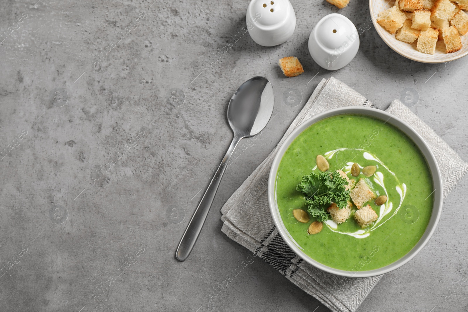 Photo of Tasty kale soup with croutons served on grey table, flat lay. Space for text