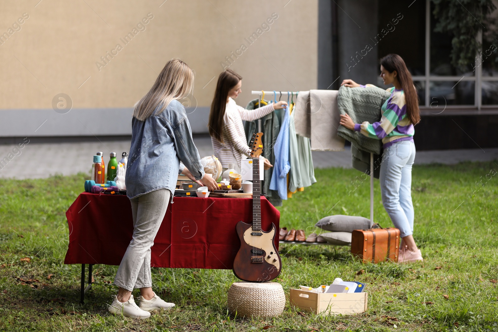 Photo of Women choosing items on garage sale in yard