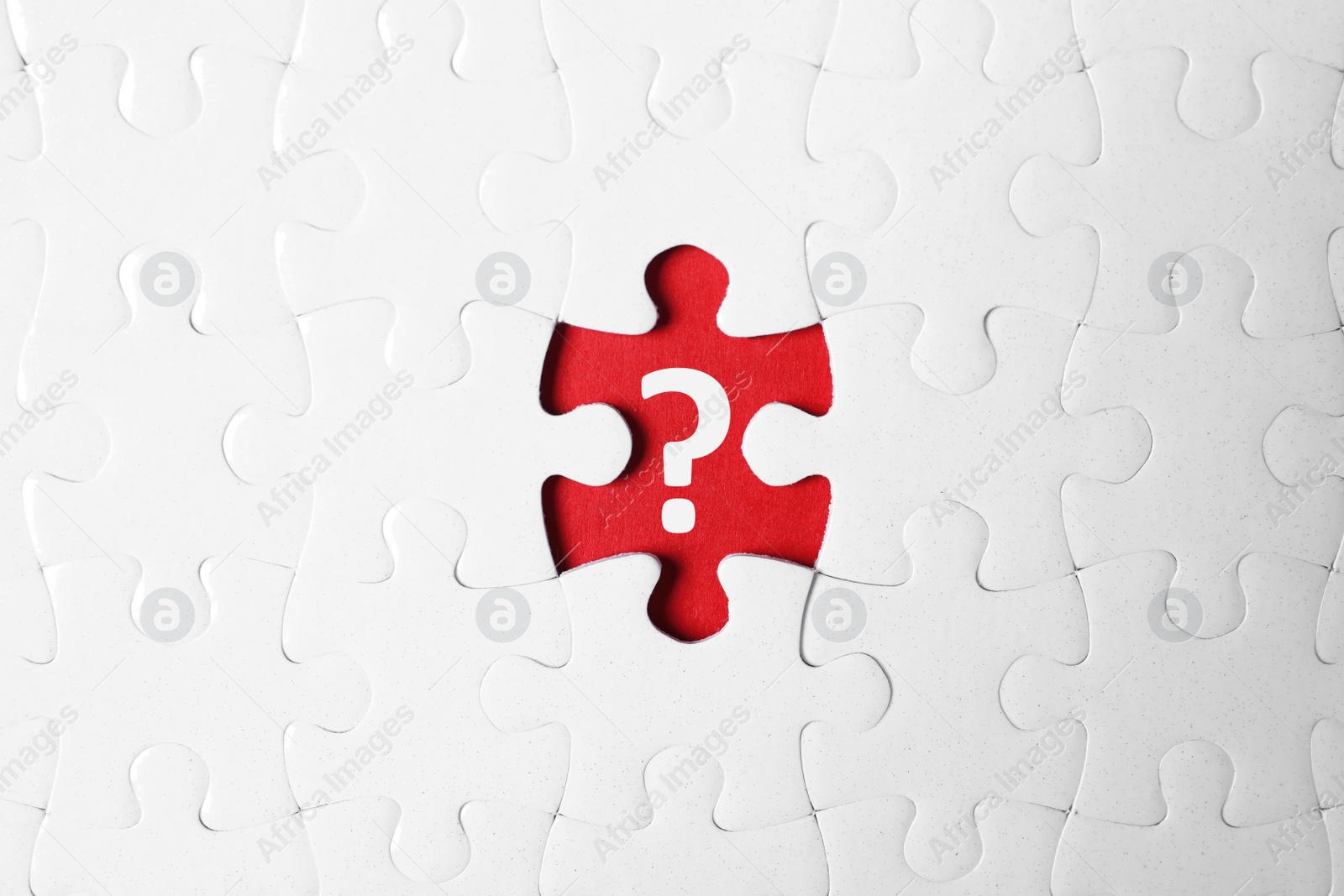 Image of White puzzle with missing piece and question mark on red background, top view