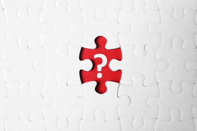 Image of White puzzle with missing piece and question mark on red background, top view