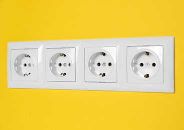 Power sockets on yellow wall, closeup. Electrical supply