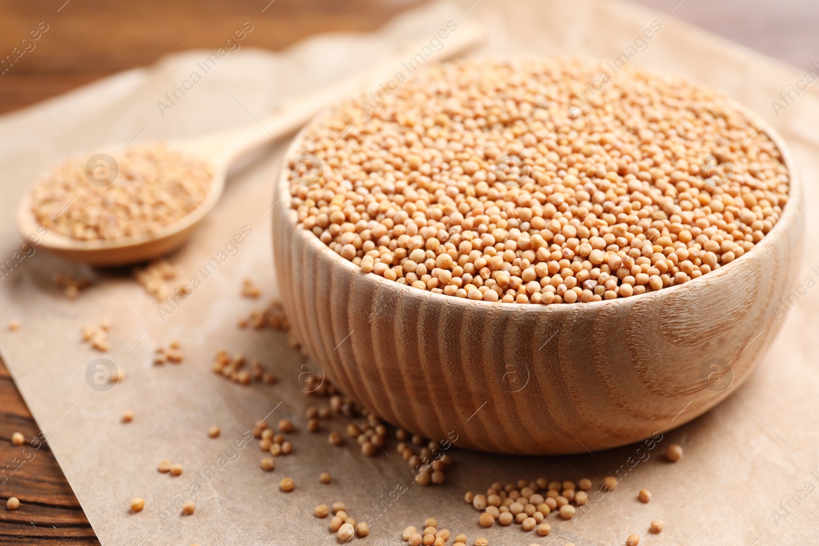 Photo of Mustard seeds in wooden bowl on table, closeup