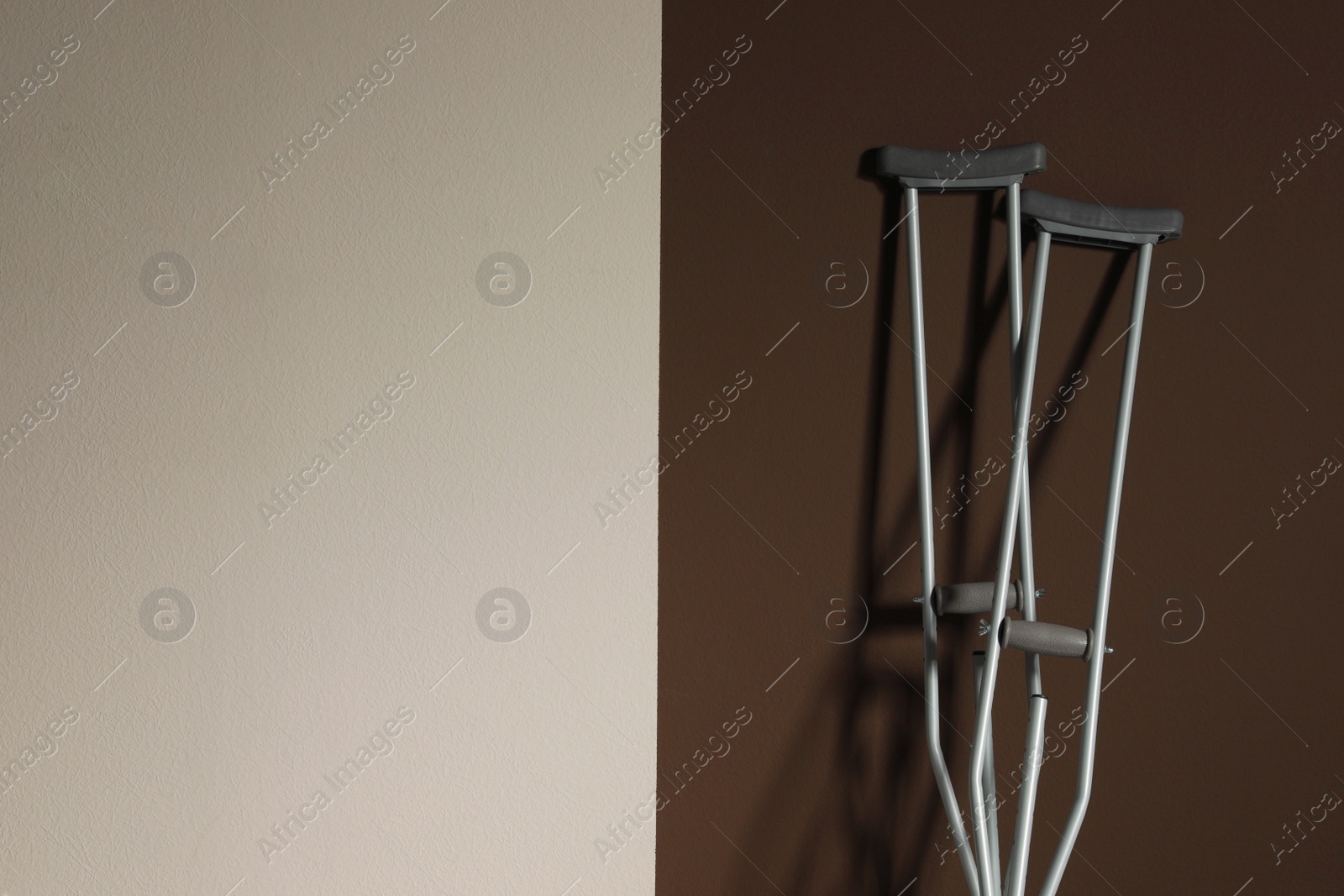 Photo of Pair of axillary crutches on color background. Space for text