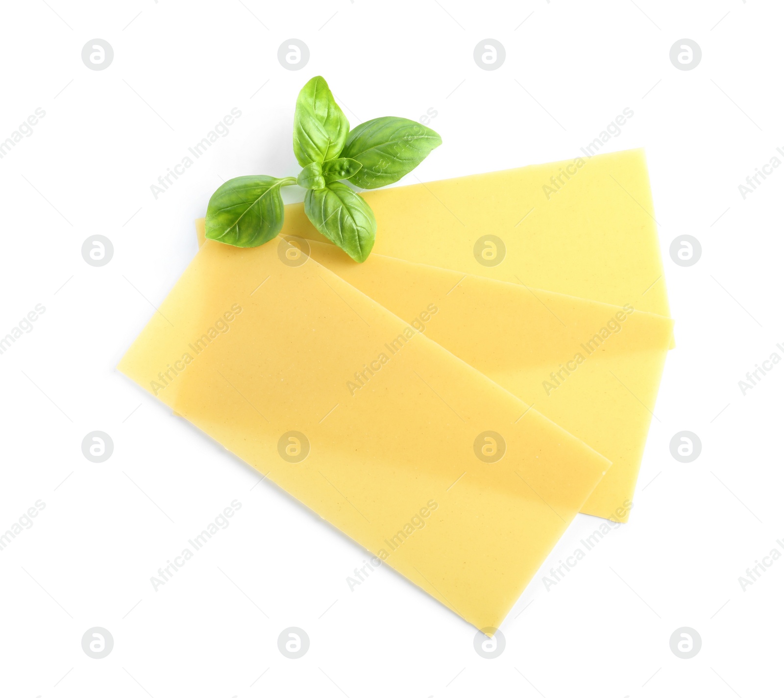 Photo of Uncooked lasagna sheets and basil on white background, top view