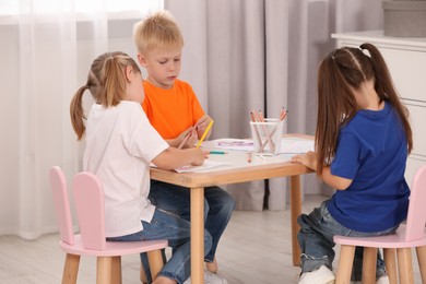 Cute little children drawing at desk in kindergarten
