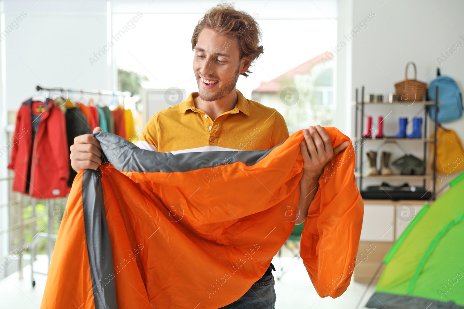 Photo of Young man choosing sleeping bag in store