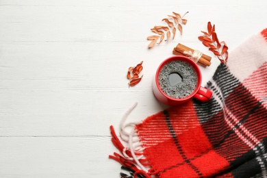 Flat lay composition with hot drink and warm plaid on white wooden table, space for text