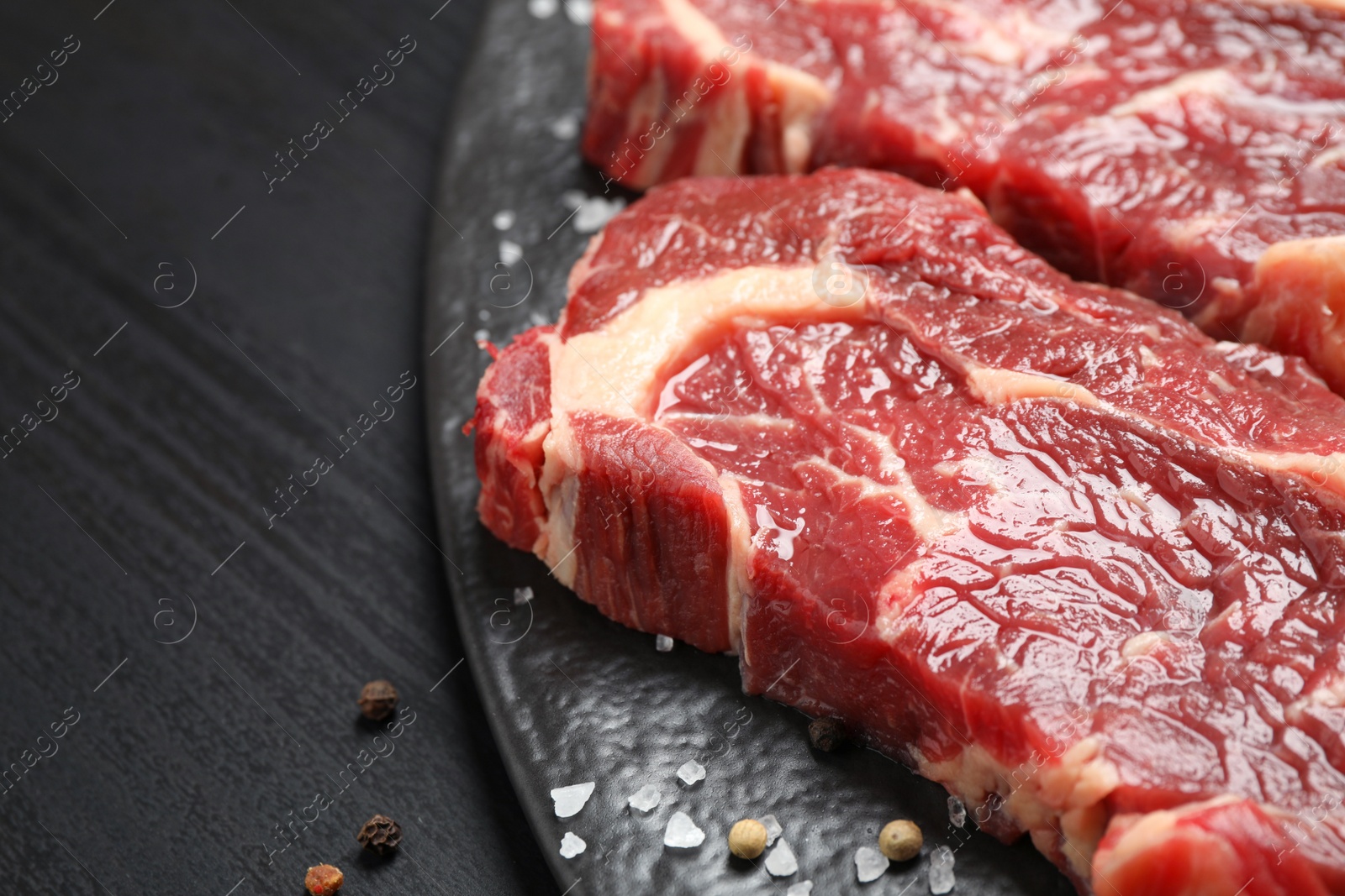 Photo of Fresh marbled meat steaks on slate board, closeup