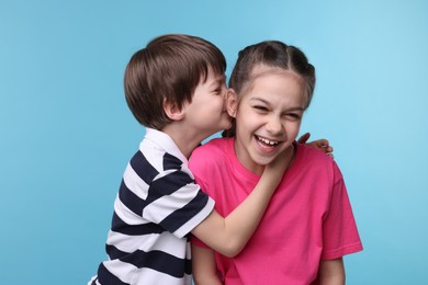 Happy brother and sister on light blue background