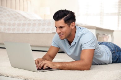 Photo of Man using laptop for search on floor at home