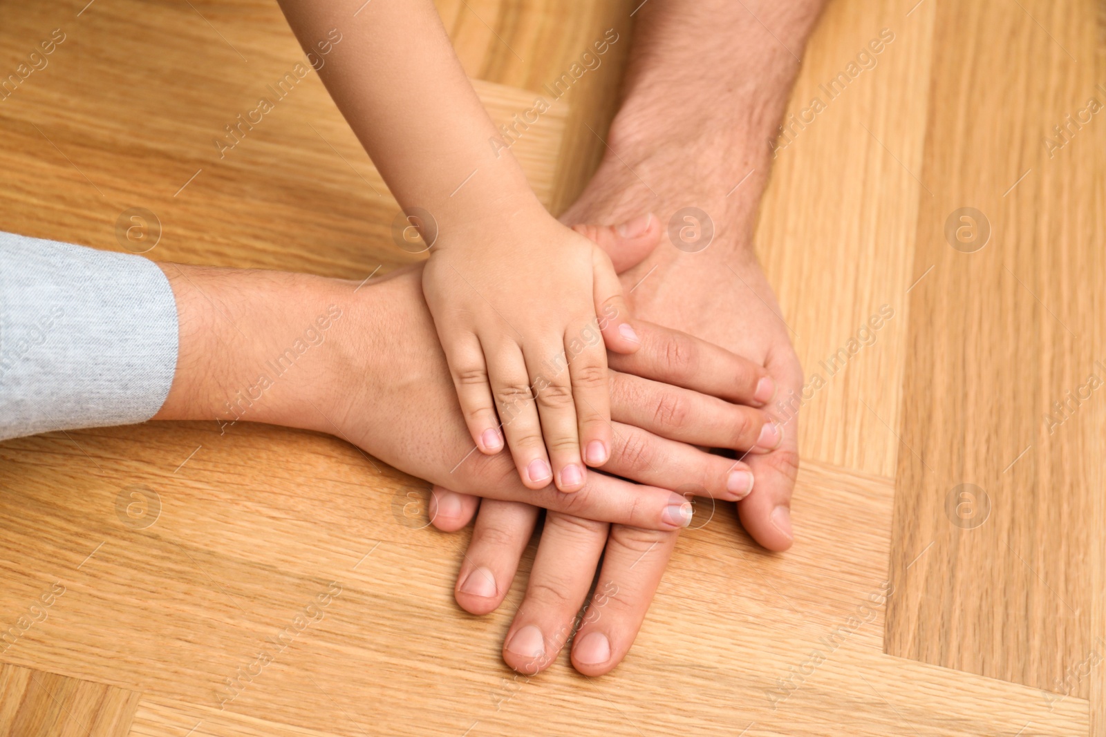 Photo of Happy family holding hands on wooden background, closeup